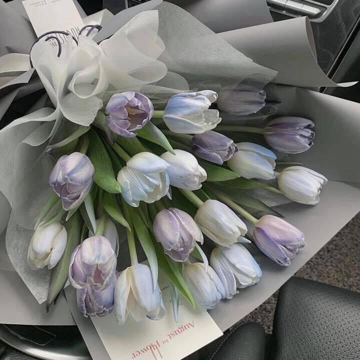 a bouquet of tulips sitting on top of a car seat next to a note