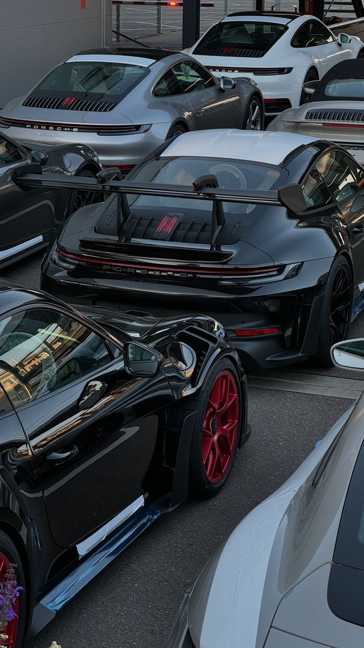 there are many cars that are parked in the parking lot and one is black with red rims