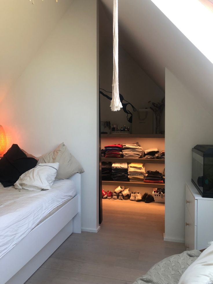 an attic bedroom with white walls and flooring, open closet to the other side