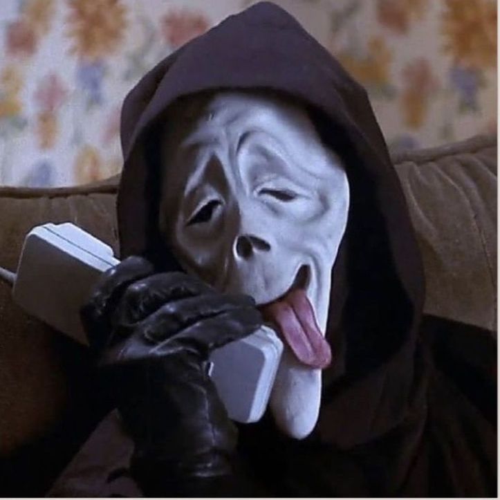 a person wearing a mask and holding a remote control in their hand while sitting on a couch