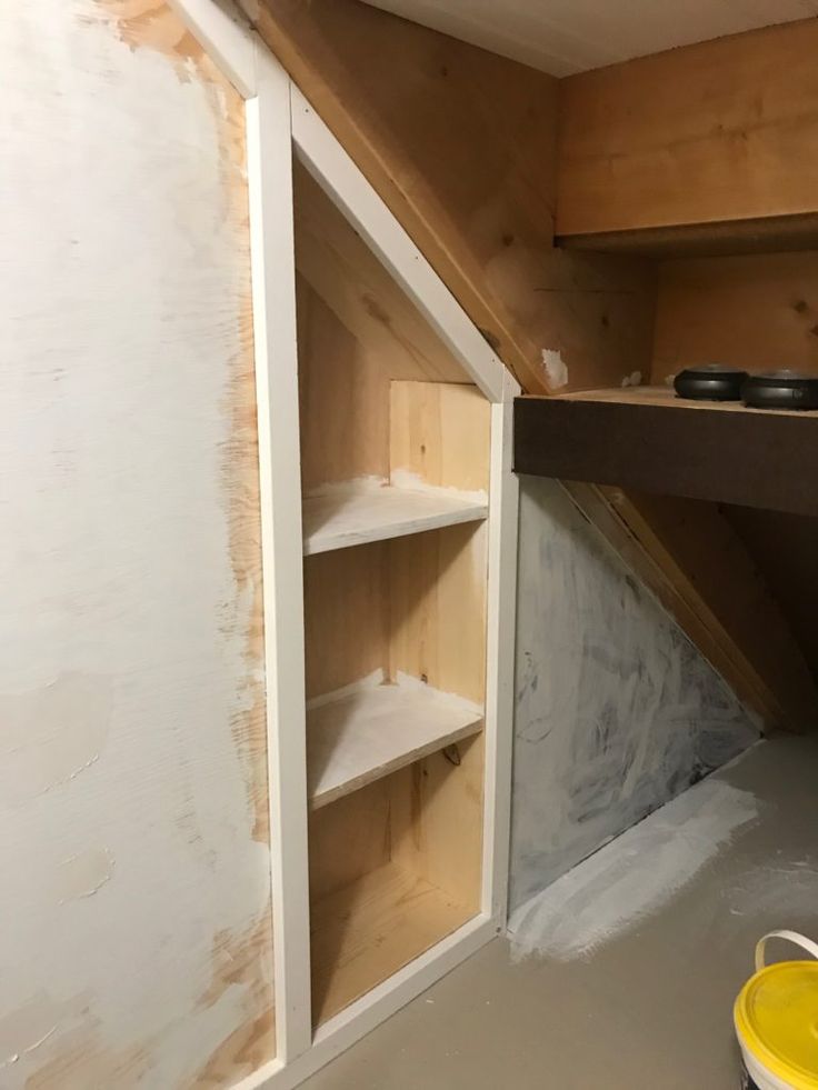 an unfinished room with shelves and buckets on the floor