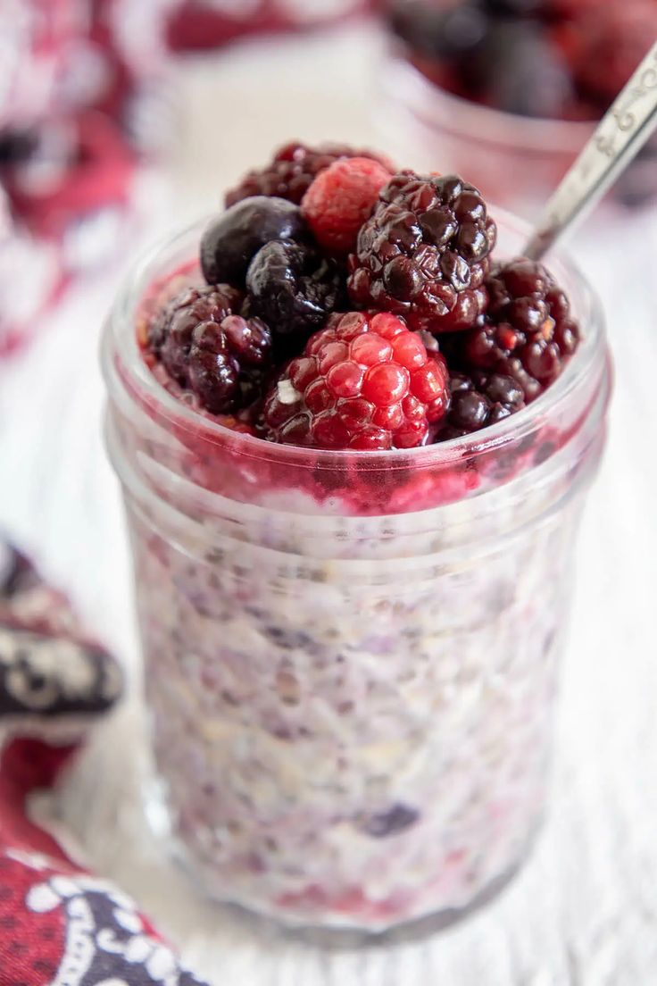 berries and chia seed pudding in a glass jar on a tablecloth with spoons