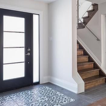 an entryway with stairs and tile flooring next to a black door on the right