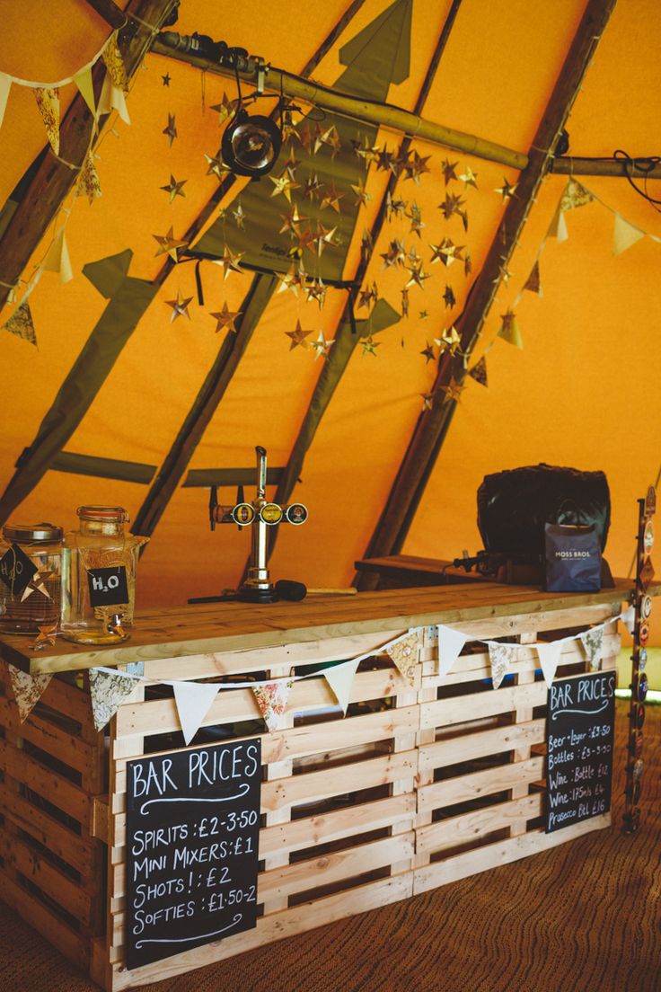 a bar made out of wooden pallets in a tent with flags and bunting