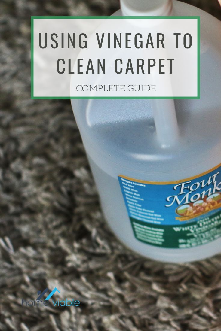 a bottle of cleaner sitting on top of a carpet next to a person's hand