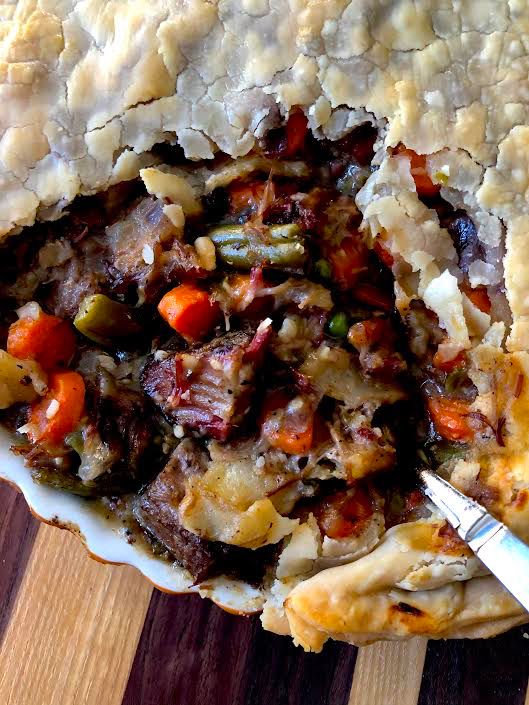 a close up of a pie on a wooden table with a fork in the middle