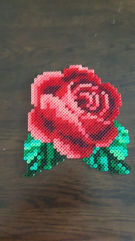 a beaded rose sitting on top of a wooden table