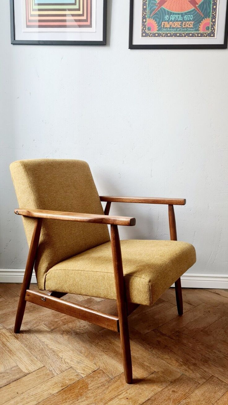 a chair sitting on top of a hard wood floor next to two framed pictures above it