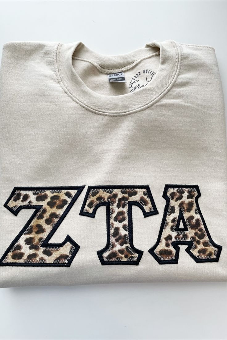 a white t - shirt with the letters zzac printed in leopard print on it