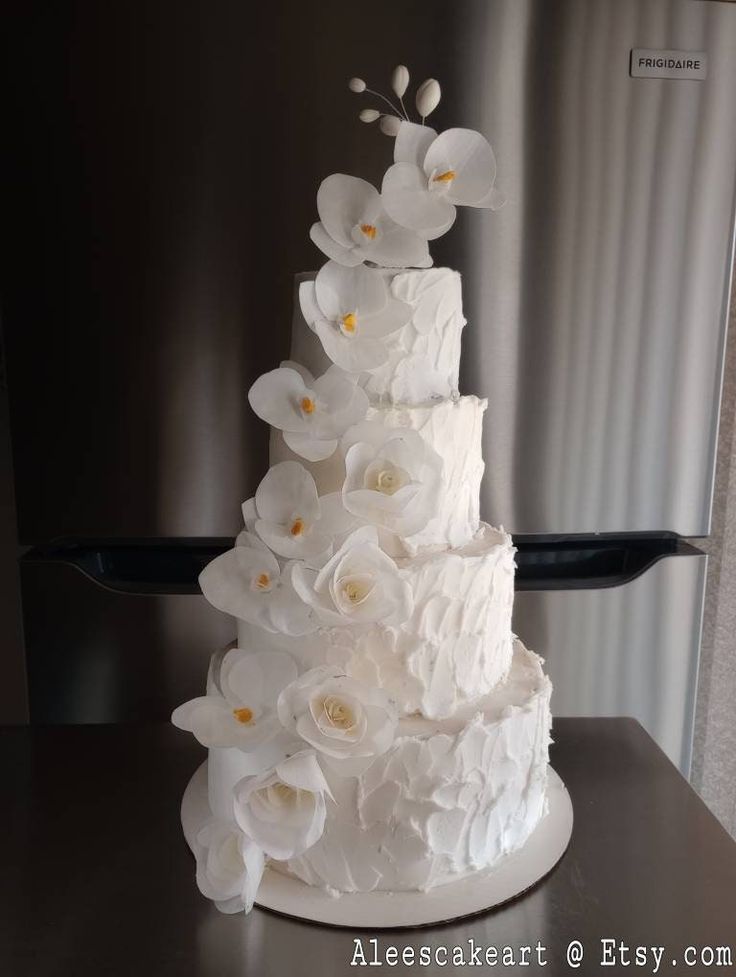 a three tiered cake with white flowers on top