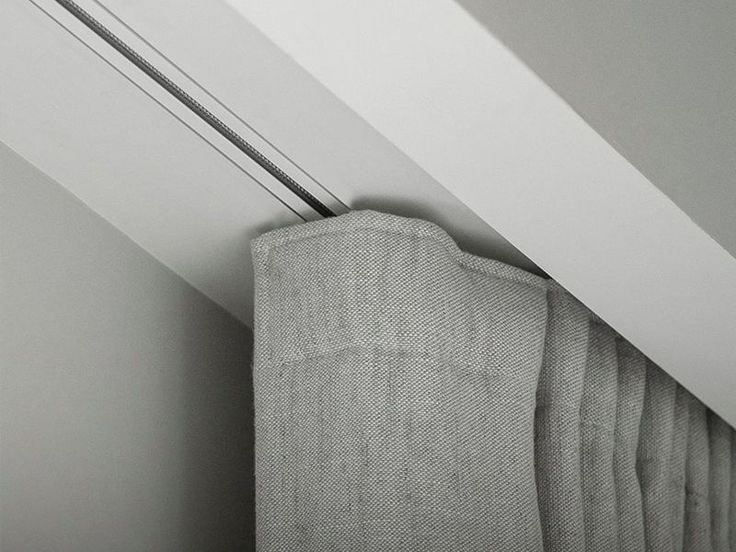 a curtain is hanging on the side of a window in a room with white walls