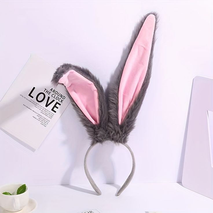 a pink bunny ears headband on top of a white desk next to a book