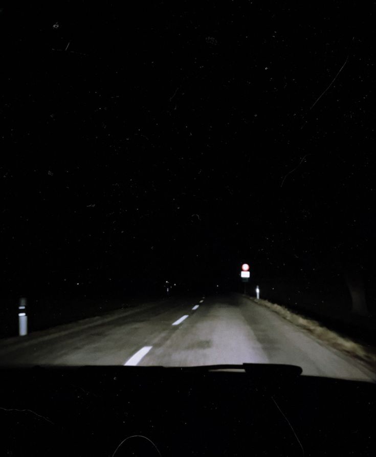 a car driving down a dark road at night