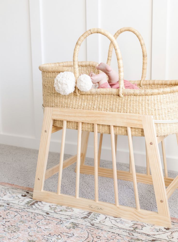 a baby sleeping in a wicker bassinet next to a rug on the floor