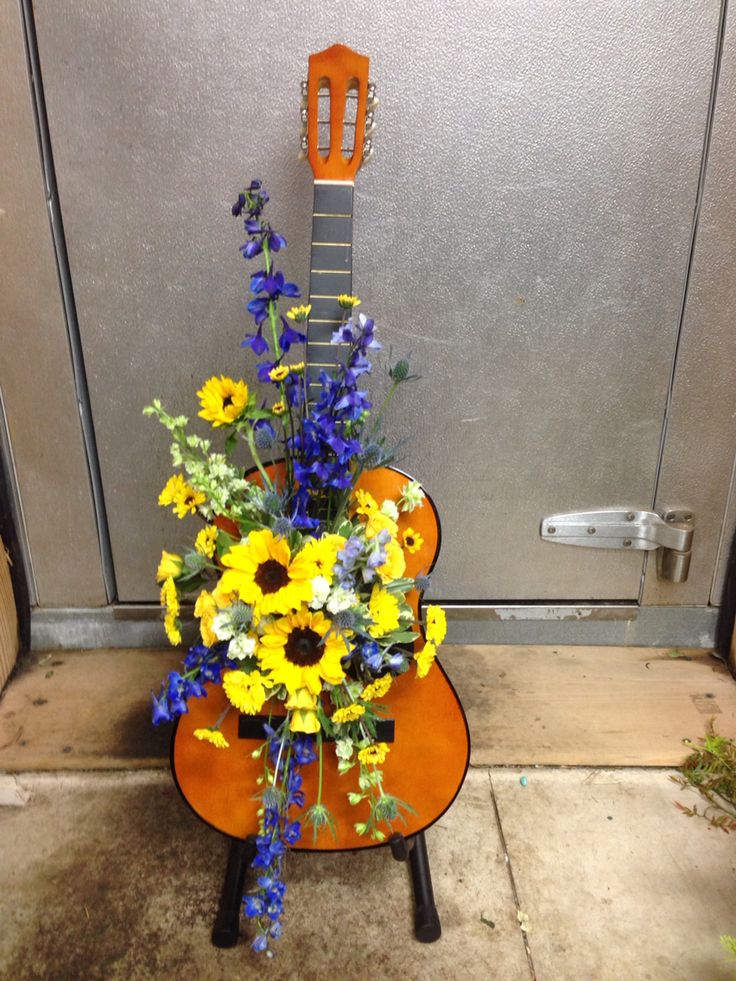 a guitar shaped arrangement with flowers in front of a door handle on an orange chair