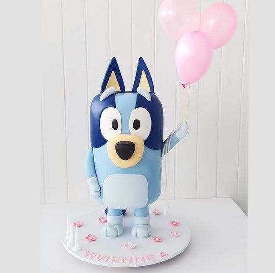 a cake that looks like an animal holding balloons