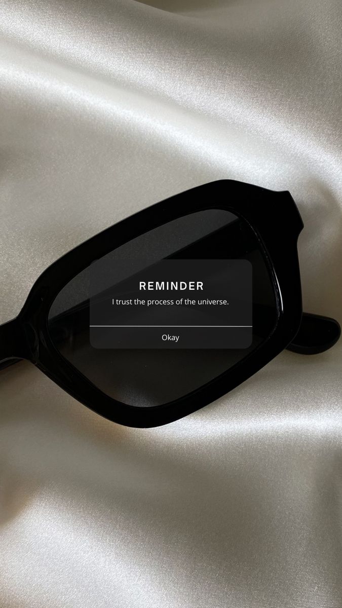 a pair of black glasses sitting on top of a white satin covered surface with the words reminder