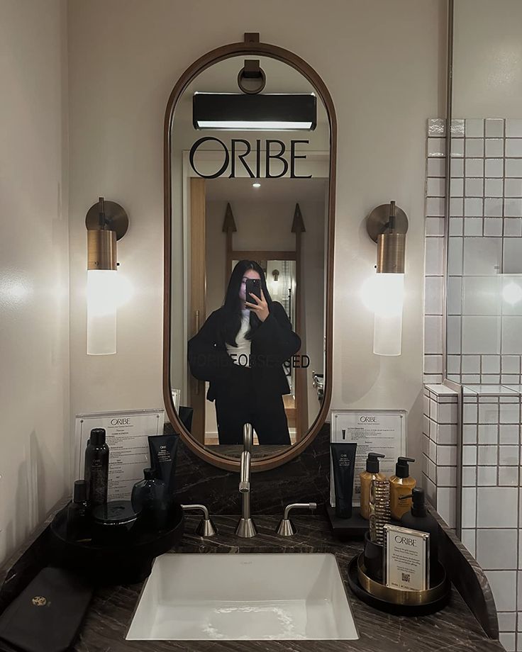 a woman taking a selfie in the bathroom mirror with her reflection on the wall