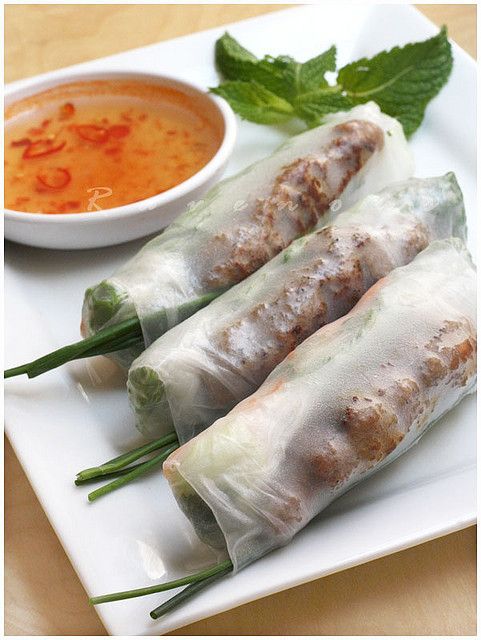 three spring rolls on a plate with dipping sauce