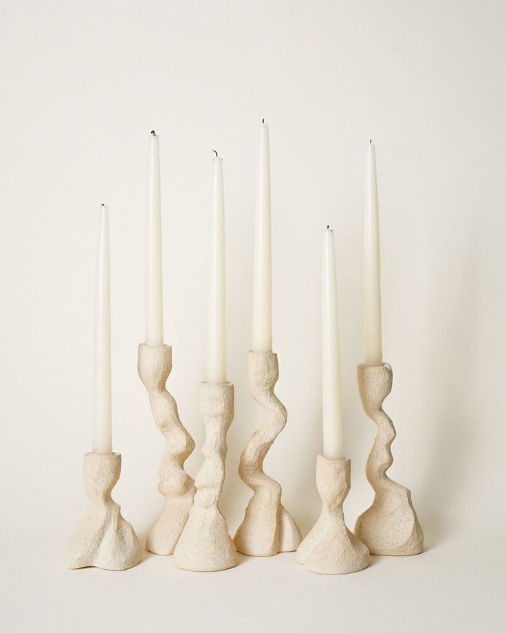 four white candles are lined up next to each other with one candle in the middle