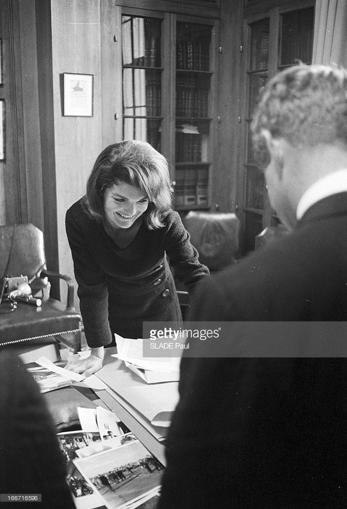 a woman sitting at a table in front of a man and looking at papers on the table