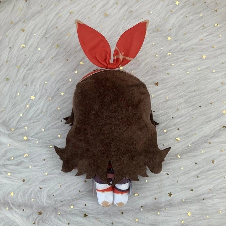 a stuffed animal with a red bow on it's head laying on a white blanket