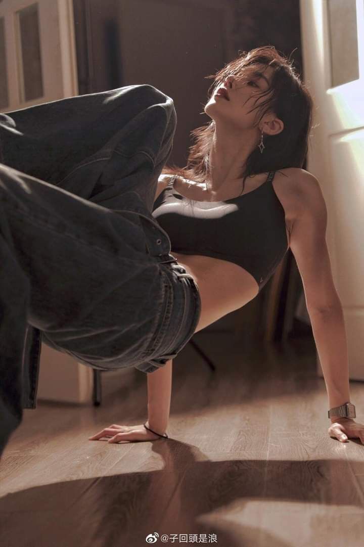 a woman in black shirt and jeans doing a handstand on wooden floor next to door