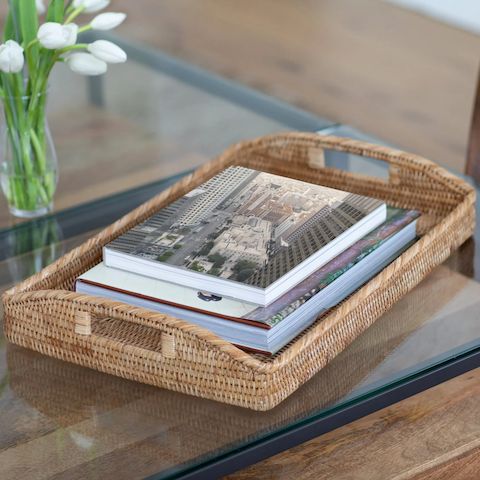 a wicker basket with books on top of it sitting on a glass coffee table