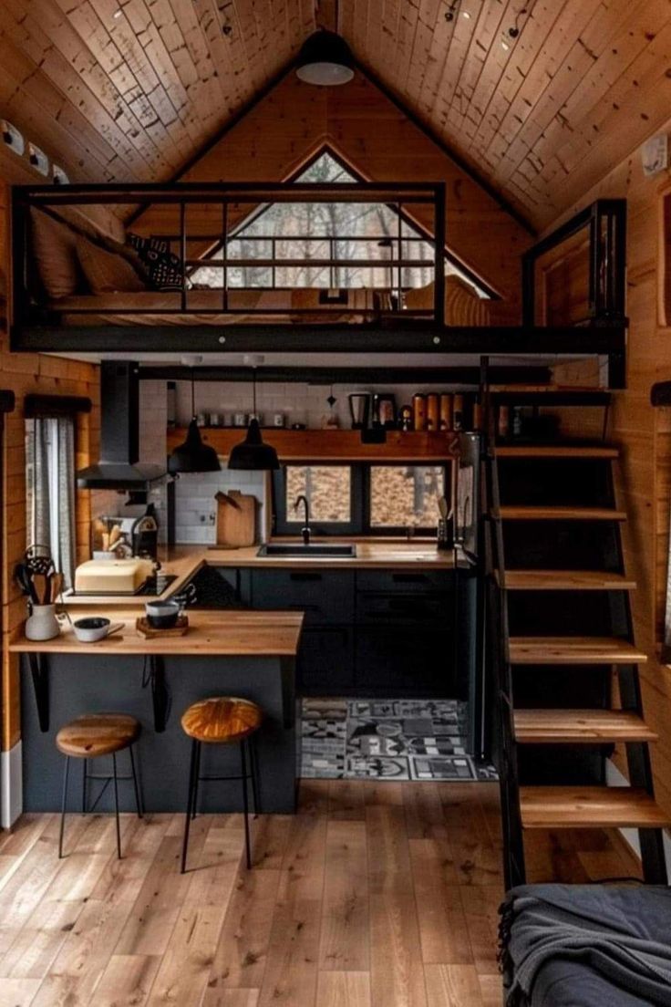 the interior of a tiny cabin with stairs leading up to an upper level kitchen area