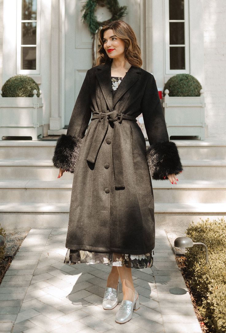 Chic and classy. Stay warm and stylish this season with the Pookie Coat in Black. Made of cozy black wool fabric, this knee-length coat features a v-shaped faux fur collared neckline and long fitted sleeves with faux fur cuffs. The button-up style with functional buttons and removable waist tie add an elegant touch, while the fully lined design ensures comfort and warmth. Black Wool Fabric, Thanksgiving Dress, Fur Cuffs, Knee Length Coat, Girls Holiday Dresses, City Woman, Fitted Sleeves, White Dress Party, Holiday Party Dresses