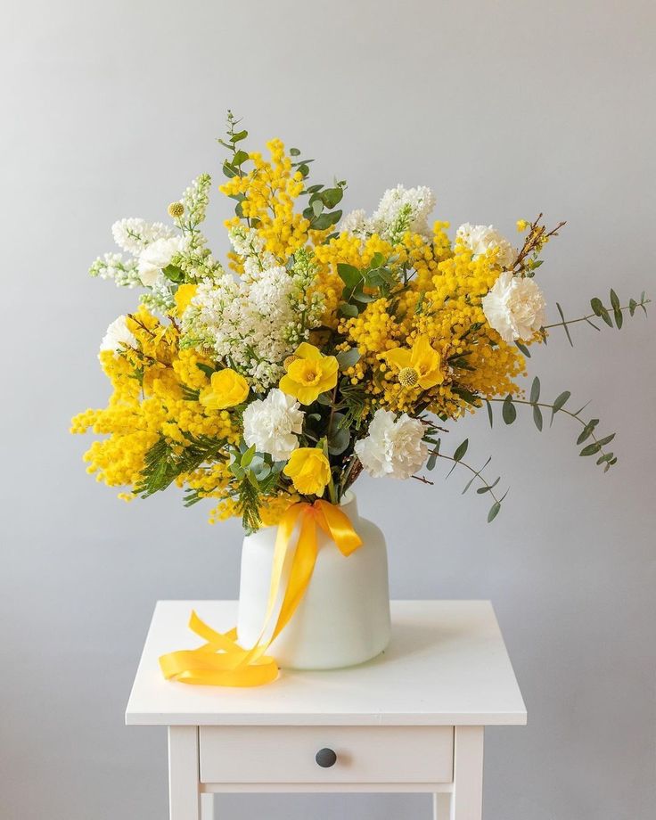 a white vase with yellow and white flowers