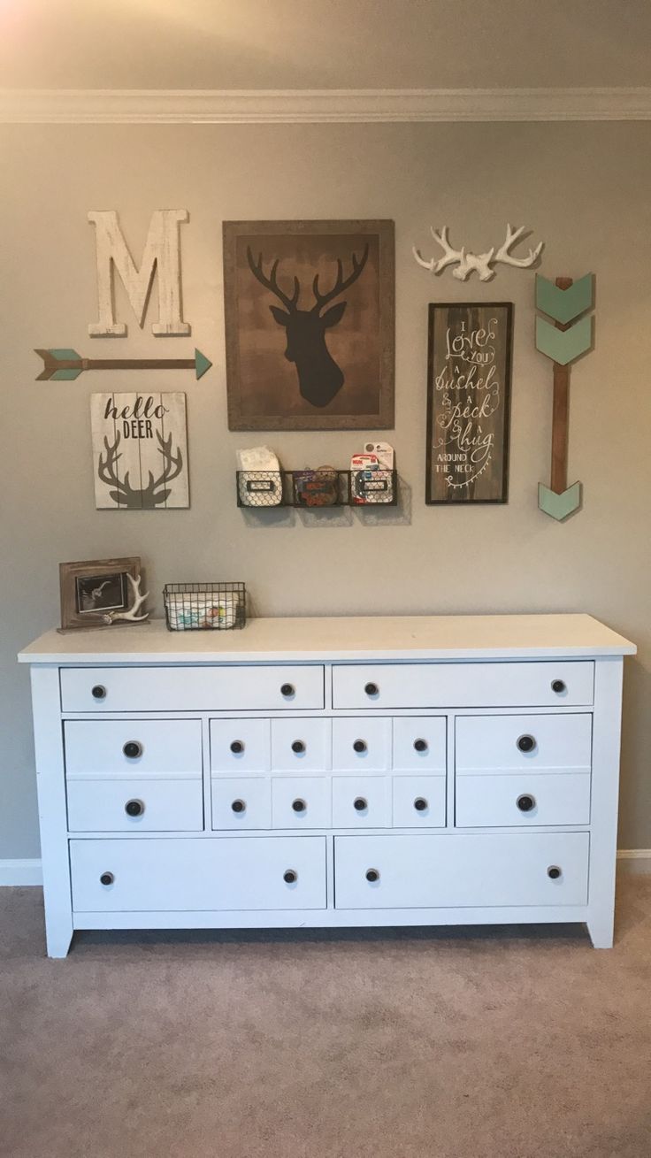 a white dresser sitting in a bedroom next to a wall with deer head on it