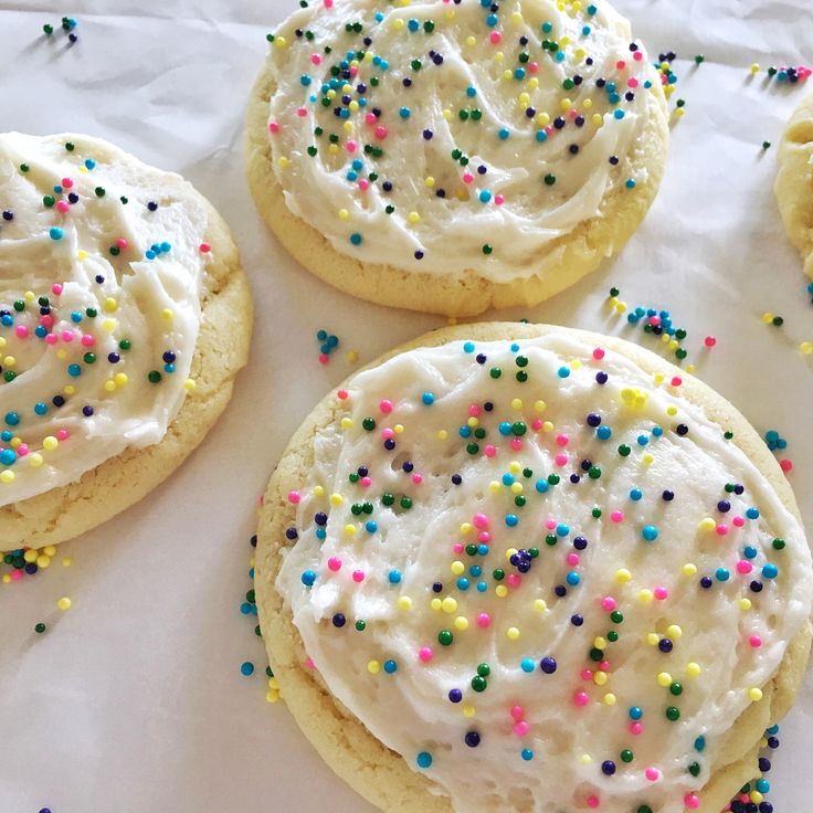 four cookies with white frosting and sprinkles