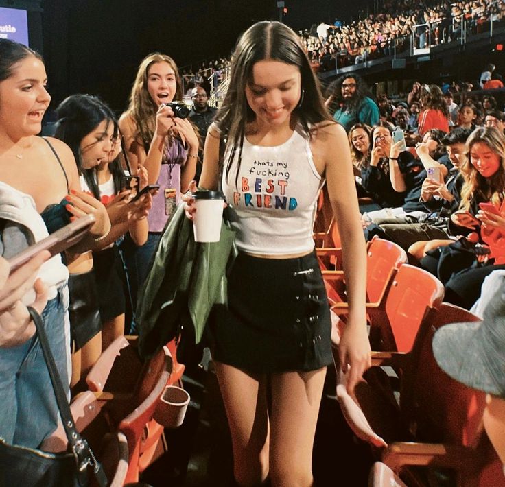 a woman in a short skirt is walking through the stands at a sporting event with fans