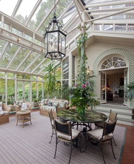 the inside of a house with glass walls and lots of plants on it's patio