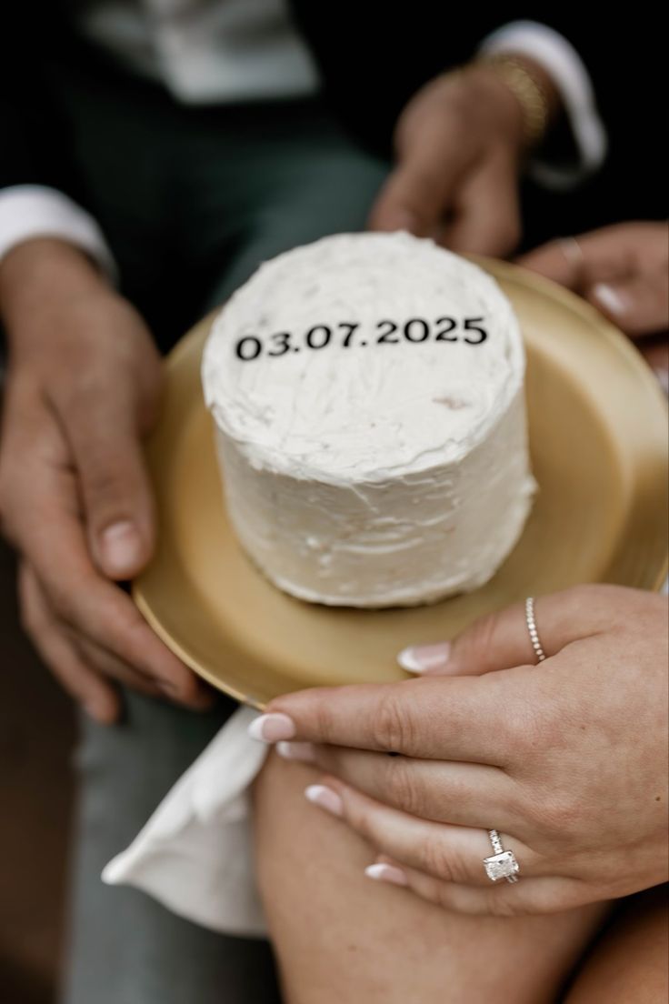 a man and woman holding a cake on top of a plate with the number twenty five