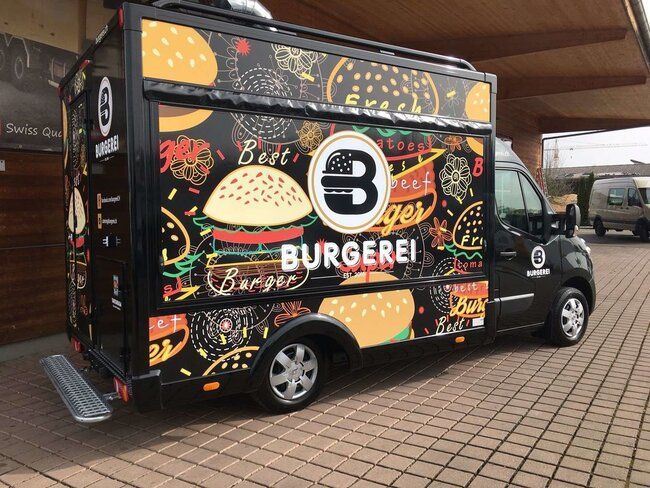 a black food truck parked in front of a building