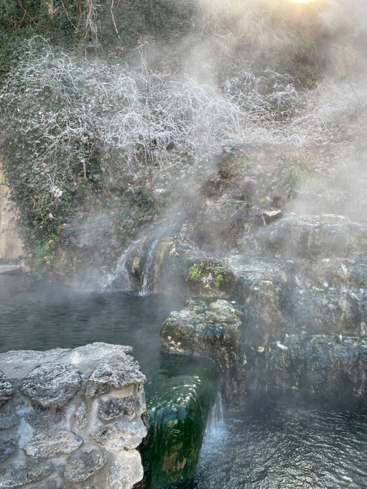 a hot spring in the middle of a river with steam rising from it's sides