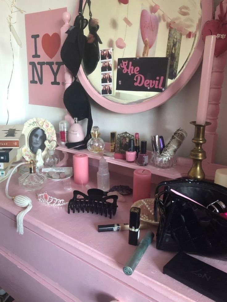 a pink vanity with makeup and accessories on it