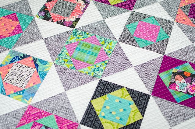 a close up of a quilt with many different designs on it, including squares and flowers