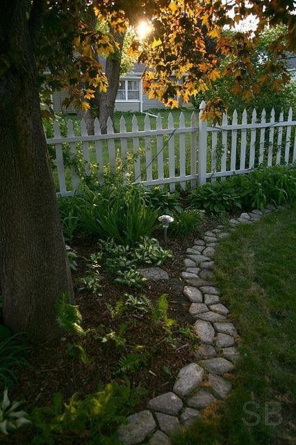 a white picket fence next to a lush green yard