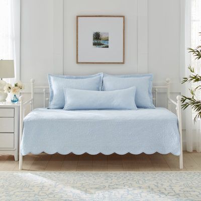 a white day bed with blue sheets and pillows