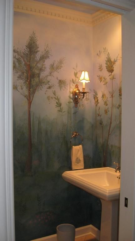 a bathroom with a painting on the wall next to a white sink and light fixture