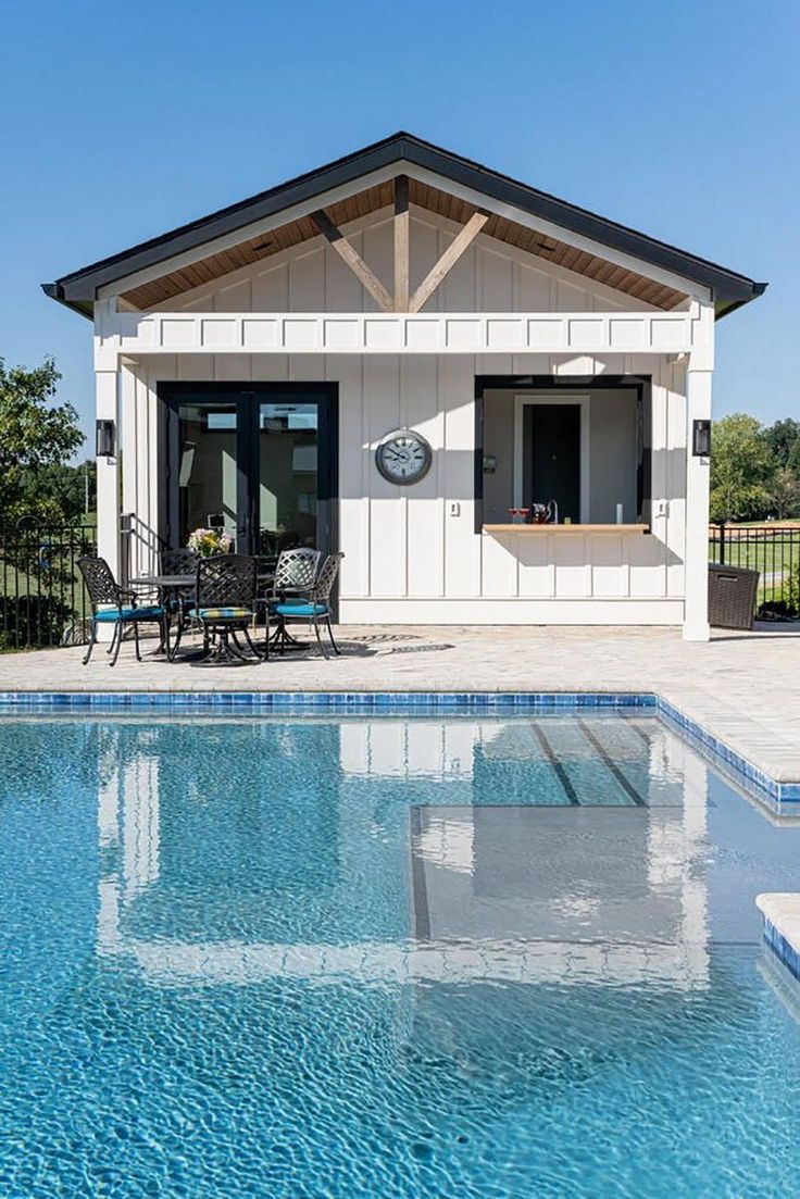 a house with a swimming pool in front of it and an outdoor dining area next to the pool