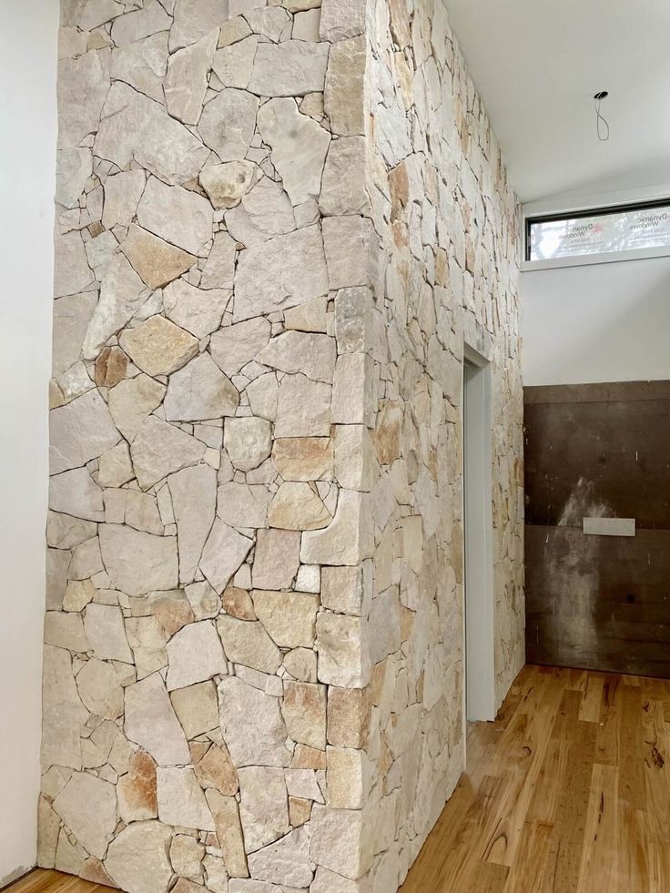 a room with wood floors and a stone wall in the corner, next to an open door