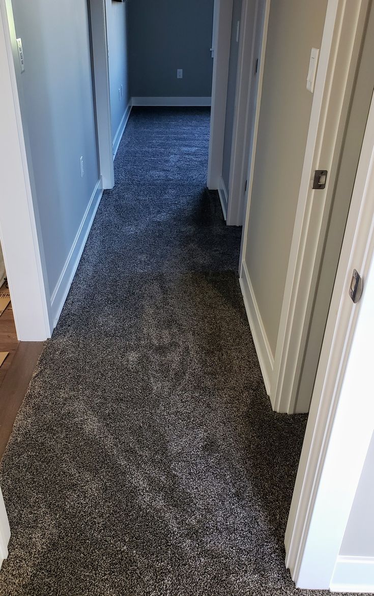 an empty hallway with carpeted floors and white trim on the door way to another room