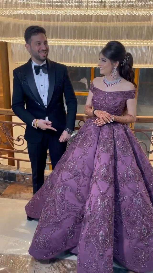 a man in a tuxedo standing next to a woman in a purple dress