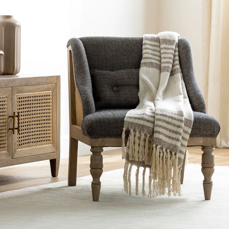 a chair with a blanket on top of it next to a table and vases