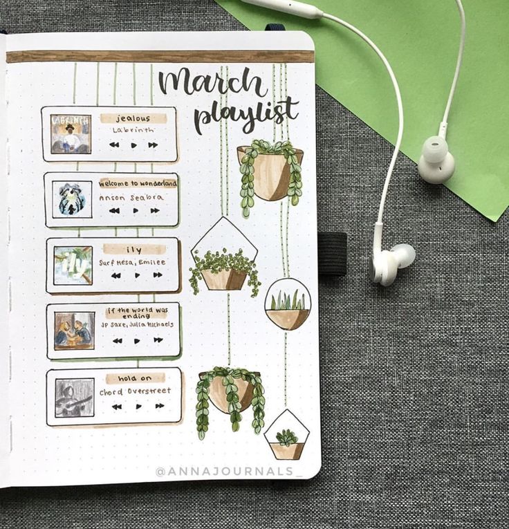 an open planner with headphones on top of it next to earbuds and a green envelope