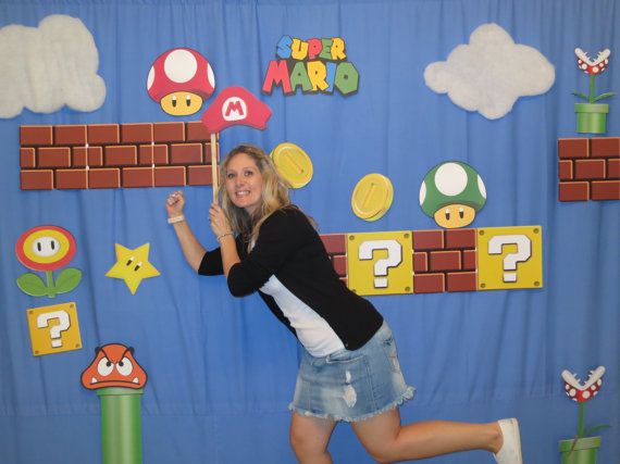 a woman posing for a photo in front of a backdrop with mario and other characters